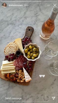 an appetizer board with cheese, olives, crackers and wine on it