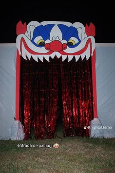 a red and white stage curtain with a clown face on it's side in front of a wall