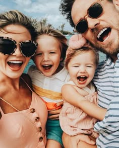 a man, woman and two children are posing for a photo together on the beach