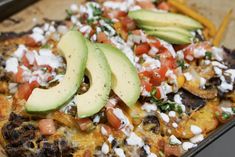 an enchilada topped with avocado and tomatoes