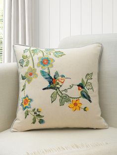 a white couch with a floral embroidered pillow on it