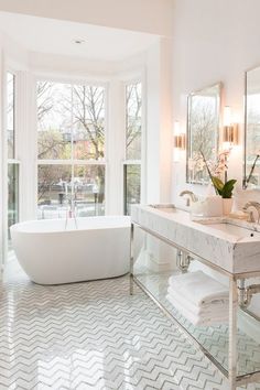 a bathroom with a tub, sink and large windows