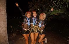 three young women dressed in costumes posing for the camera at night with palm trees behind them