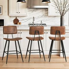 three stools in a kitchen with white cabinets and marble backsplash, along with an island