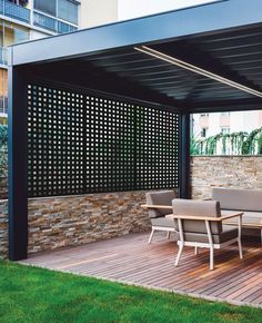 a wooden deck with chairs and tables under a pergolated roof