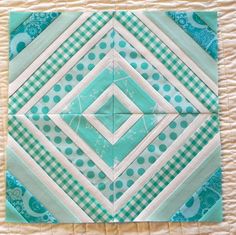 a blue and green patchwork quilt with white dots on the bottom, square in center