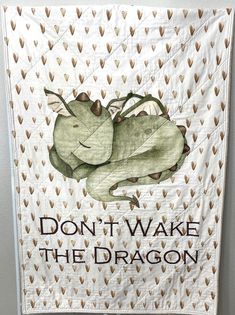 a white wall hanging with an image of two green dragon on it's side