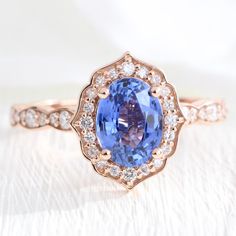 a tan gold ring with an oval blue sapphire surrounded by diamonds