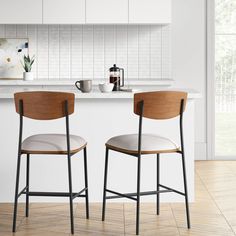 two chairs sitting next to each other in front of a white counter top and wooden floor