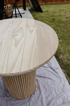 a wooden table sitting on top of a piece of cloth next to a green field