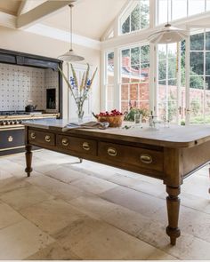 a large kitchen with an island table in front of the stove and oven, surrounded by windows