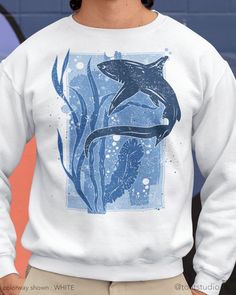 "This thresher shark sweatshirt is great for shark, beach, and marine life lovers. Great gift for anyone who spends their time enjoying the surf, beach sunsets, snorkeling, scuba diving, and other water activities. FABRIC CONTENT:  - Fabric content : 50% cotton / 50% polyester - Medium-heavy fabric (8.0 oz/yd² (271.25 g/m   FIT & CONSTRUCTION :  - Runs true to size (sizing runs slightly larger for women, as this is a unisex style) - Without side seams, knit in one tubular piece to reduce fabric waste - Highly elastic ribbed knit collar and neck seam helps retain neck shape    SIZING : Please see sizing image as reference - SIZE / WIDTH / CHEST / BODY LENGTH / SLEEVE LENGTH:  - S / 20\" / 40\" / 27\" / 20\" - M / 22\" / 44\" / 28\" / 21\" - L / 24\" / 48\" / 29\" / 22\" - XL / 26\" / 52\" / Shark Head Sweater, Shark Como Hoddies Gery, Shark 3 Shirt, White Crew Neck Top With Shark Design, Shark Clothes, Thresher Shark, Artwork Easy, Shark Silhouette, Shark Sweatshirt