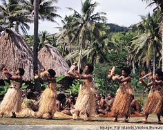 some people are dancing around in grass skirts and straw skirted dresses with palm trees behind them