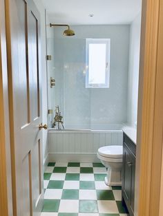 a bathroom with green and white checkered flooring on the walls, toilet and bathtub