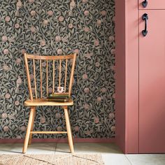 a wooden chair sitting in front of a pink wall