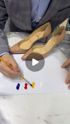 a man in a business suit is painting shoes with acrylic paint and a pencil