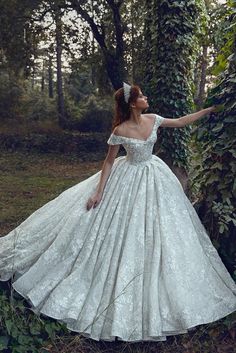 a woman in a white wedding dress standing next to a tree and ivy covered wall