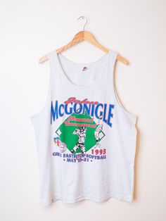 "Vintage graphic tank top with fantastic full front print. Four color graphic print celebrates the \"John McGonigle Memorial Girl's Fastpitch Softball Tournament of 1995\". Tank is excellent mid-weight cotton in ash heather gray.  Great for layering or worn on it's own. Tank brand is Fruit of the Loom. Size is XL, see measurements below for a good fit.  Some very slight discolorations spots towards belly, only noticeable if you are looking for them.  Great condition otherwise. Item is sold as is Sleeveless Graphic T-shirt For Sports Events, Sports Tank T-shirt With Graphic Print, Retro Graphic Print Tank Top, Retro Crew Neck Tank Top With Graphic Print, Retro Tank Tops With Letter Print, Retro Graphic Print Sleeveless Tank Top, Graphic Print Tank Top For Summer Sports Events, Retro Racerback Tank Top With Graphic Print, Summer Graphic Print Tank Top For Sports Events