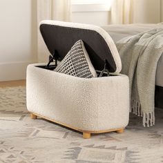 a white ottoman sitting on top of a rug next to a bed