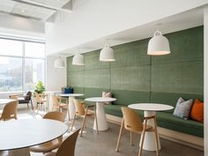 a room with tables, chairs and couches next to a large window on the wall