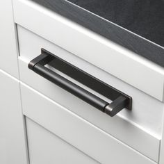 a black handle on a white cabinet door