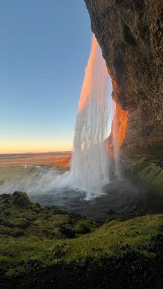 a large waterfall is coming out of the side of a cliff