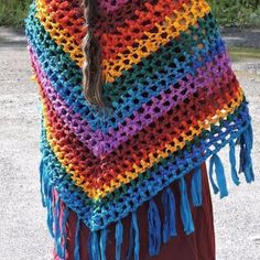 a woman wearing a multicolored crocheted shawl with tassels