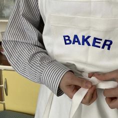 a person wearing an apron with the word baker embroidered on it's chest and holding a napkin in their hands