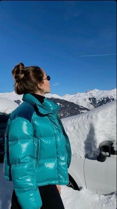 a woman standing in the snow next to a car