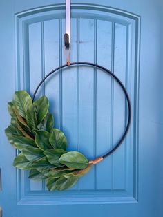 a blue door with a wreath hanging on it's side and a pair of scissors next to it