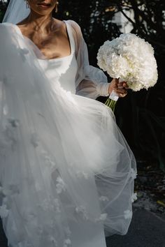 a woman in a white dress holding a bouquet of flowers