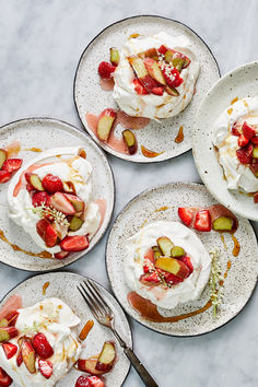 four plates topped with desserts on top of a white marble countertop next to silverware