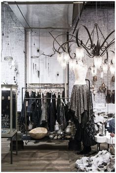 an old fashion store display with clothes on racks and chandeliers hanging from the ceiling