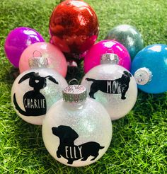 six personalized glass christmas ornaments in different colors and designs on green grass with red, pink, purple, blue, and white balls