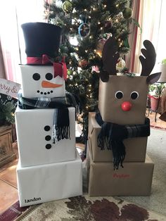 two cardboard boxes decorated like snowmen sitting in front of a christmas tree