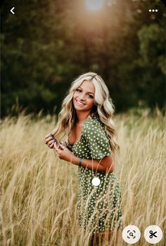 a woman standing in tall grass with her hands on her hips and smiling at the camera