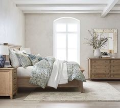 a bedroom with a bed, dresser and mirror on the wall in front of it