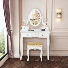 a white dressing table with a mirror and stool in front of a window overlooking the outdoors