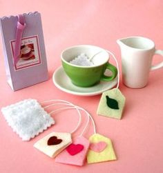 there is a cup, tea bag and two small pieces of felt on the table