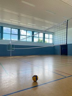 an indoor volleyball court with a net and ball on the ground in front of it