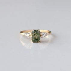 a gold ring with a green stone and three diamonds