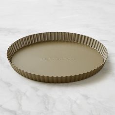 a round cake pan with scalloped edges sits on a marble countertop, ready to be used for baking