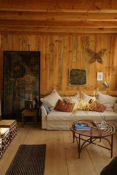 a living room filled with furniture and wood paneled walls, along with a coffee table