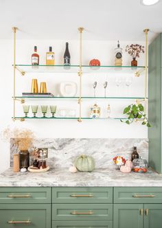 a kitchen with green cabinets and shelves filled with bottles, glasses, and other items