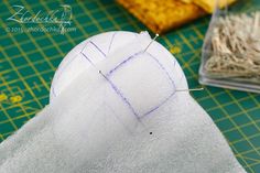 a piece of fabric with pins sticking out of it next to some other items on a cutting board