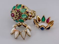 This magnificent Antique Thai Princess ring is a true gem in every sense. Crafted in 18k yellow gold, it features a stunning array of gemstones, including permanent round-cut rubies, opals, emeralds, and a mix of other precious gems.  The ring boasts a unique design with interchangeable crowns, allowing you to switch up your look effortlessly. The center peg holds a 0.05ct ruby, surrounded by eighteen small round rubies. Each crown showcases eight cabochon pear-cut gemstones, with one crown dedicated to opals, one to emeralds, and one to the enchanting mix of ruby, blue sapphire, white sapphire, amethyst, tiger eye, pink tourmaline, emerald, and citrine.  The combination of exquisite craftsmanship and a vibrant assortment of gemstones makes this ring truly one-of-a-kind. Specifications: * Antique Gold Rings, Multi Gemstone Ring, Princess Ring, Ruby Emerald, Crown Ring, 18k Gold Ring, Precious Gems, Multi Stone Ring, Multi Stone