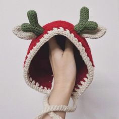 someone is holding up a crocheted strawberry hat