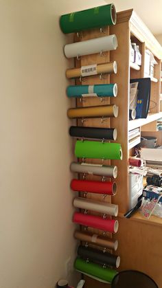 a wall mounted shelf with many different colored rolls on it and hanging from the side