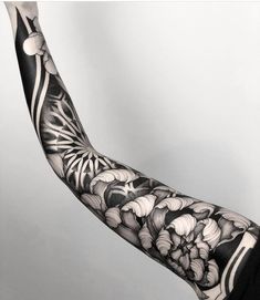 the arm is covered in black and white tattoos on it's arms, with an intricate flower design