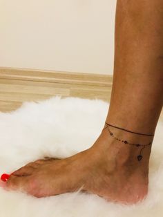 a woman's bare foot with a red toenail and black beaded ankle bracelet